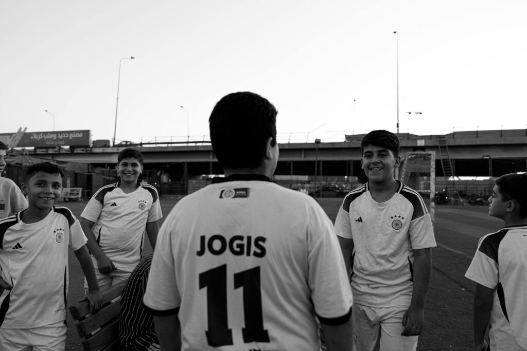 Smiling boys in soccer jerseys gather outdoors at dusk, fostering teamwork.